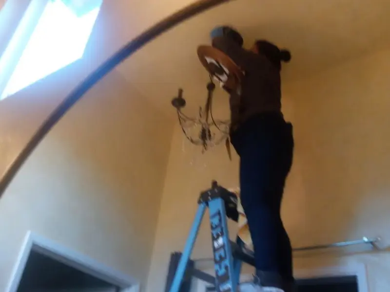 Electrician installing a chandelier in a Bethany residence